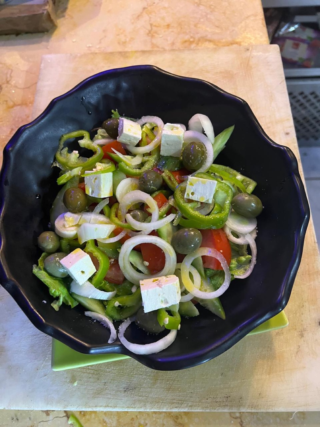 Greek-style salad with feta, olives and peppers in a black bowl