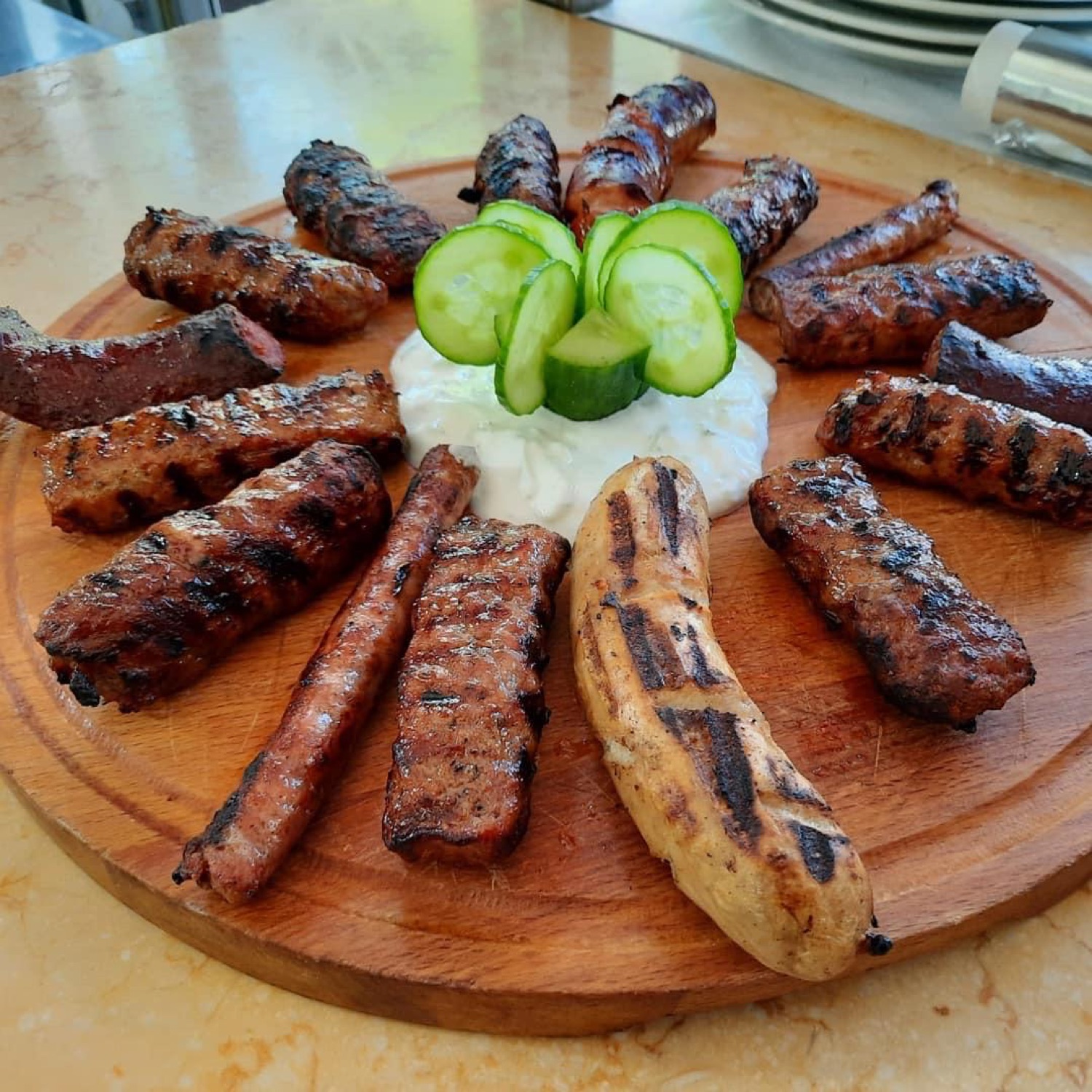 Round board of grilled sausage and meatballs with yogurt dip