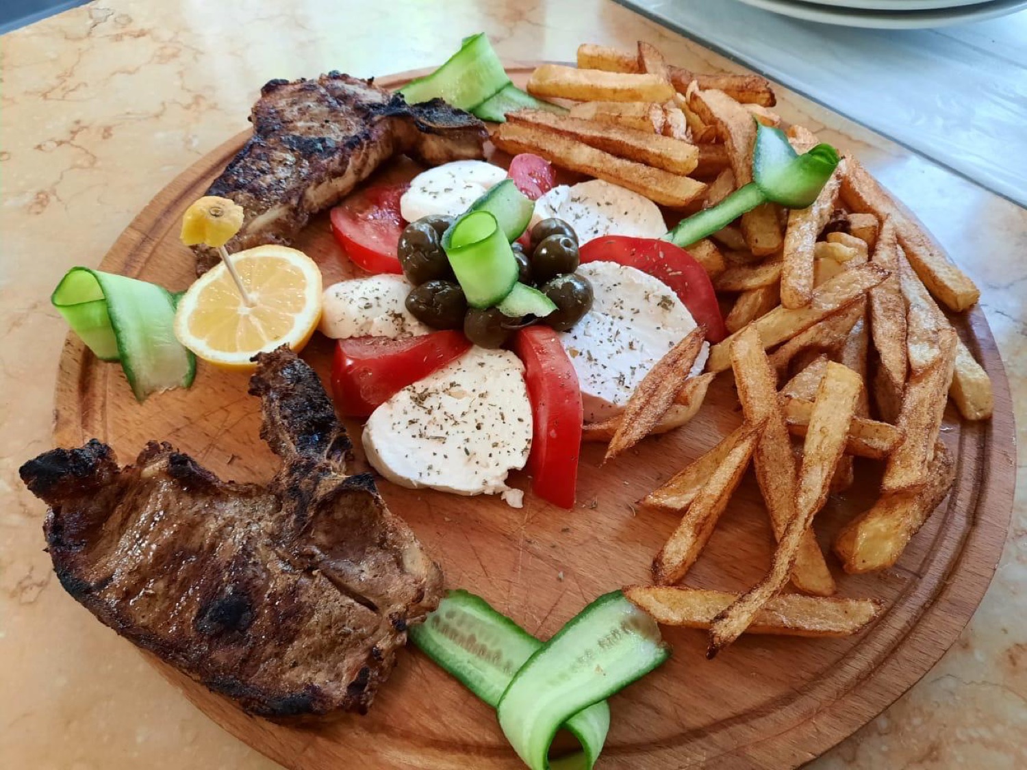 Pork chops with caprese and chips on a wooden board