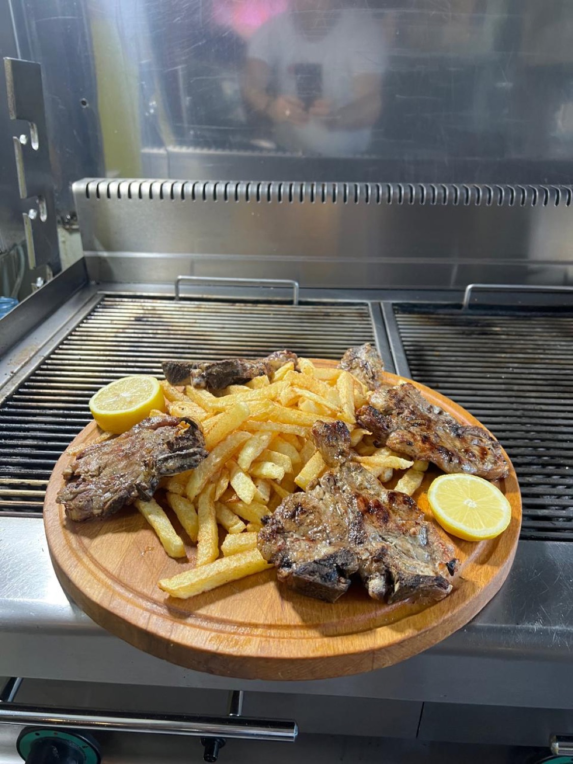 Lamb chops and chips on a board, resting on the grill
