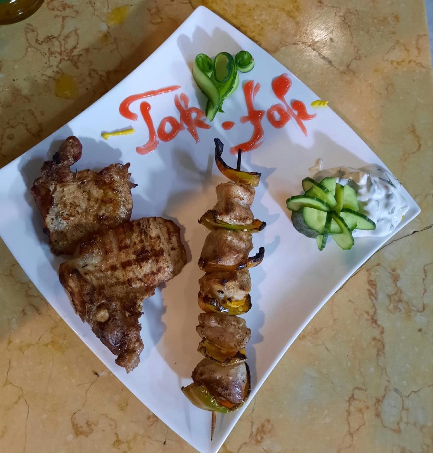 Pork chop and a chicken skewer with the Tak-Fak name in sauce